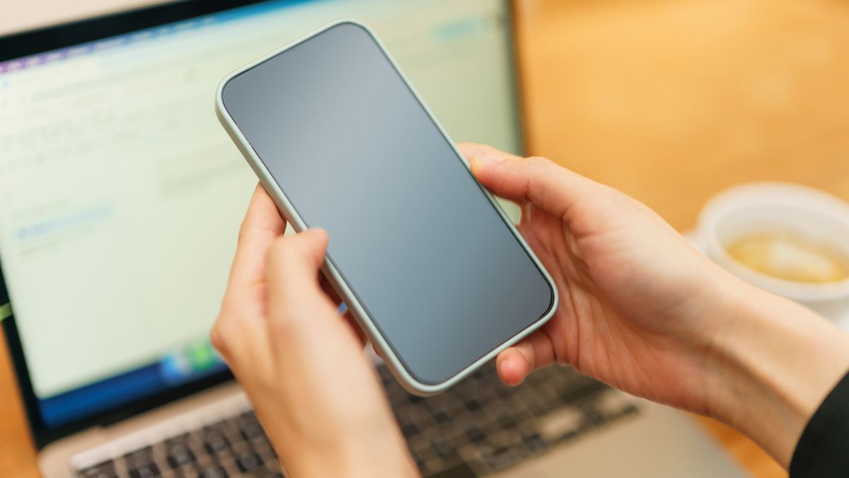 Persona revisando en el móvil un correo de captación de leads frente a un portátil