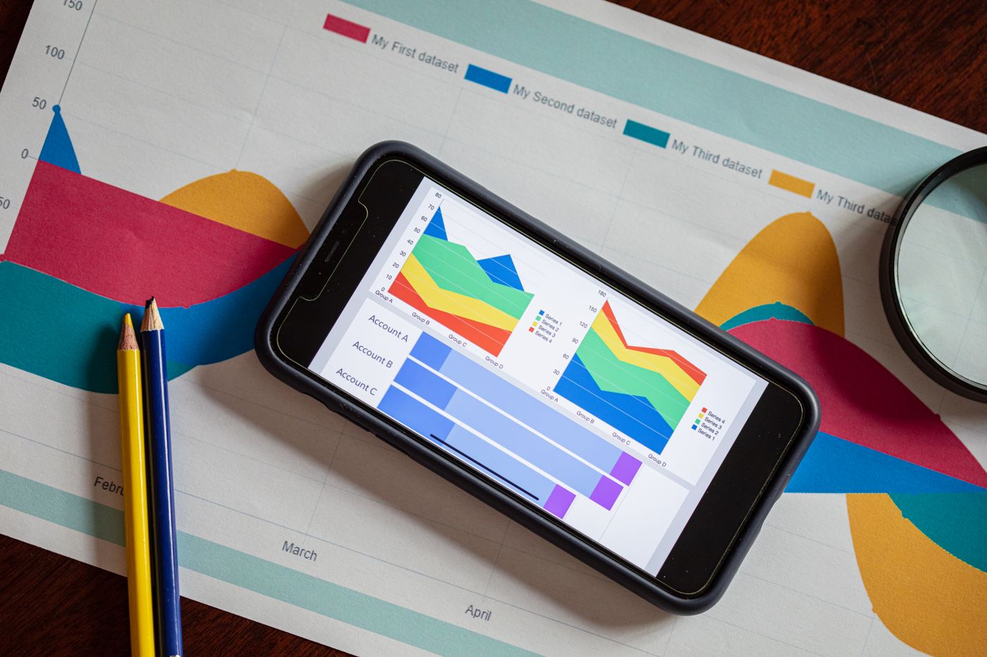 Qué incluye una auditoría SEO gratuita (y de qué desconfiar si no la incluye) 2 Movil con graficos de analitica junto a una lupa sobre la mesa