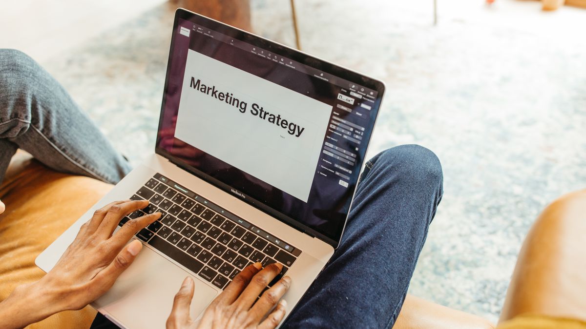 Persona trabajando en un portátil con una presentación de estrategia de marketing en pantalla