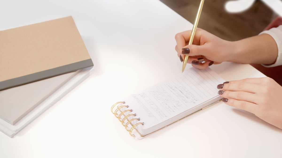 Manos tomando notas en un cuaderno durante la investigación de clientes
